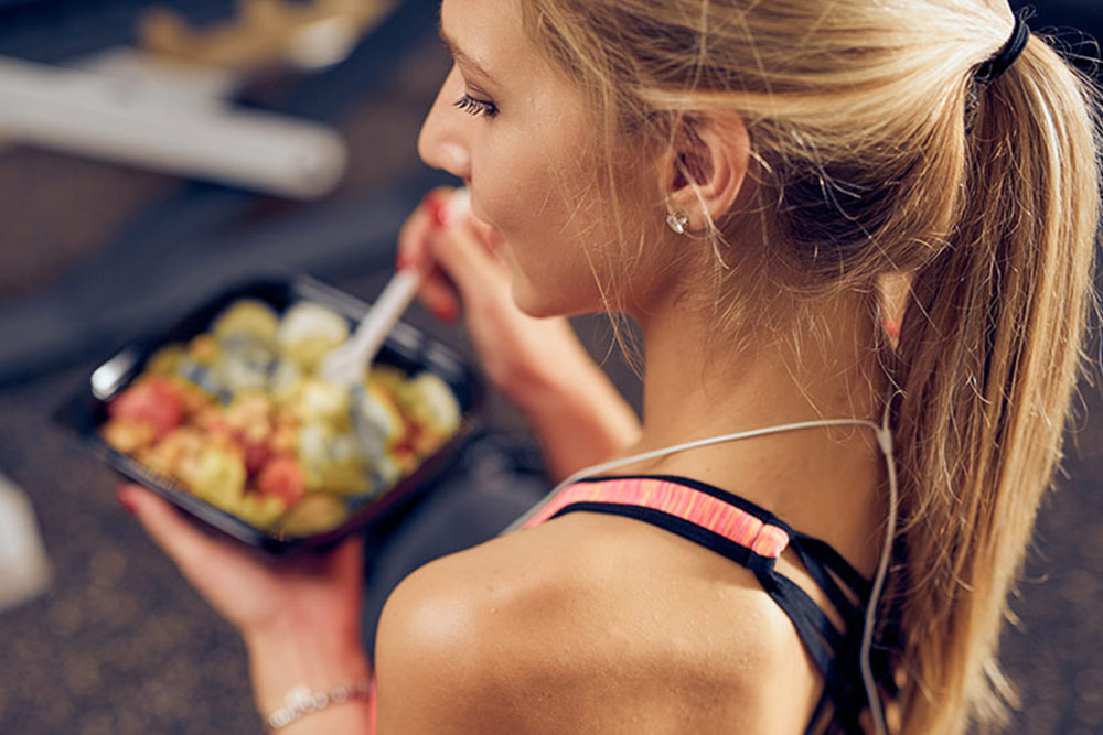 Close up of woman eating salad at the gym