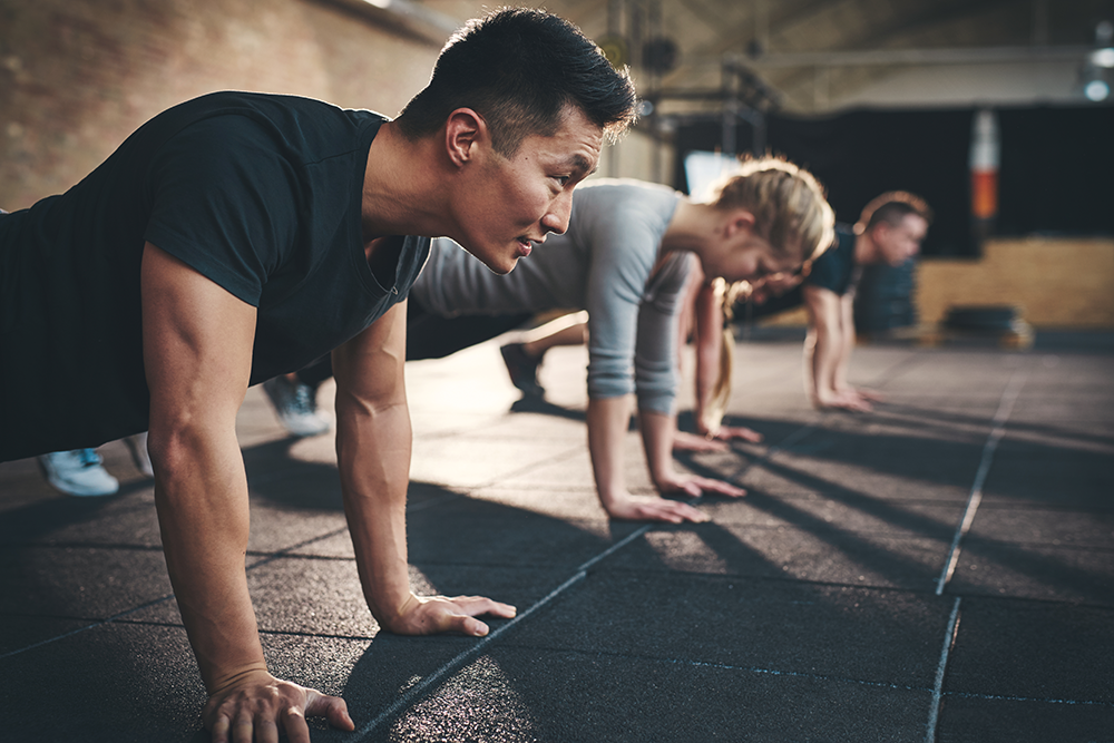 Group fitness class, multiple people in gym doing planks or pushups