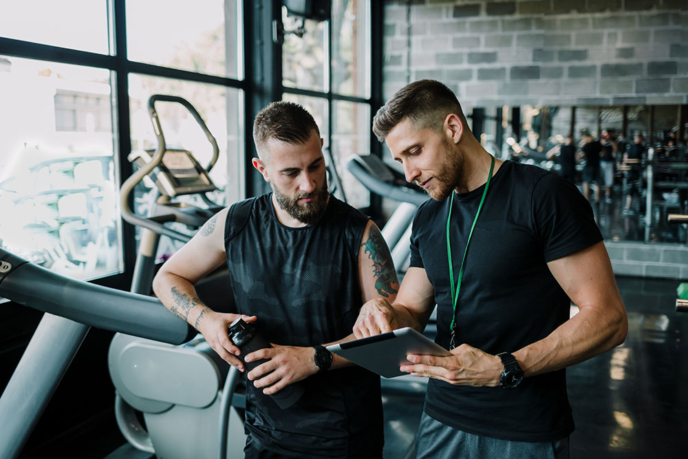 Personal trainer going over workout plans with client in gym