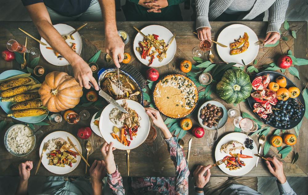 A group of friends and family pass plates around at Thanksgiving