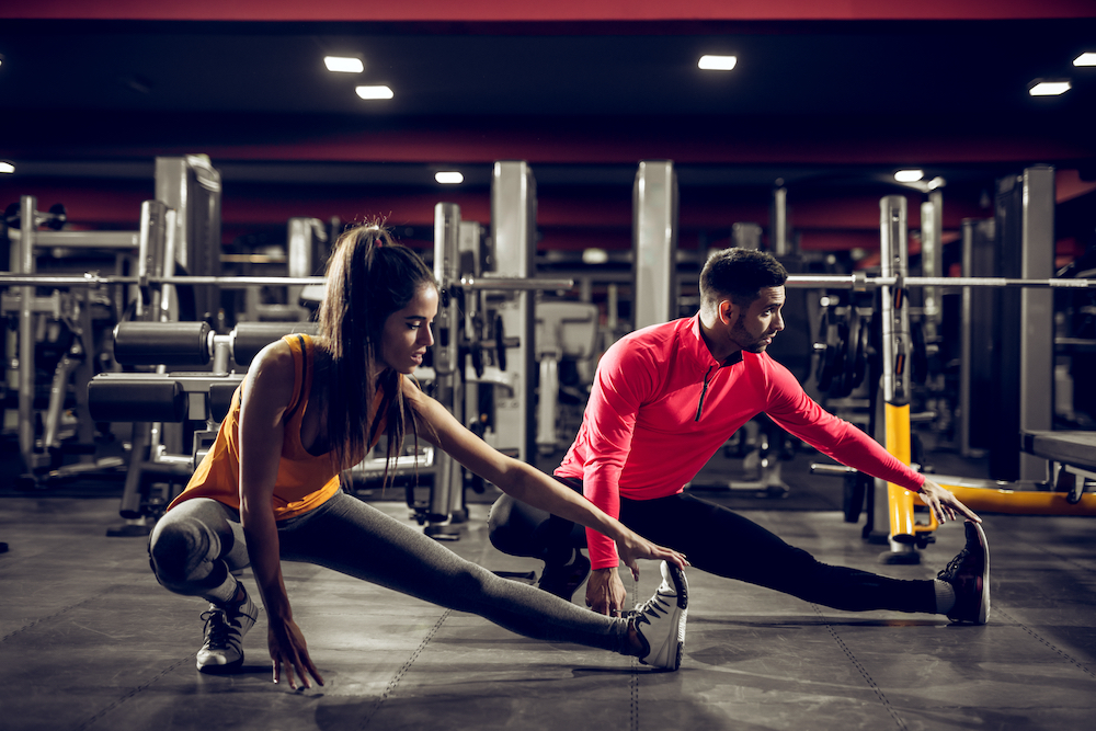 Two people stretch before a workout