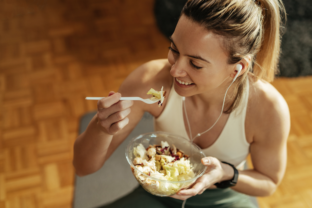 A fit woman eating a salad