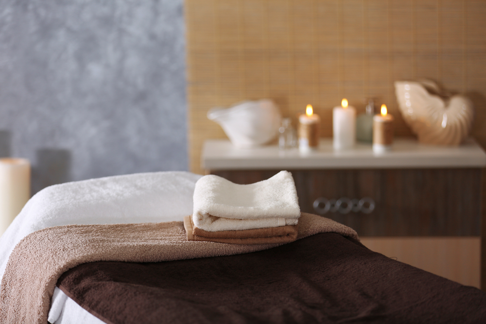 A massage bed with towel and candles at the Woodside spa Kansas City