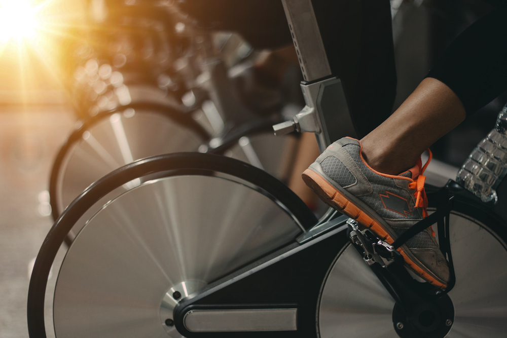 A close up shot of shoes as people take an indoor cycling class