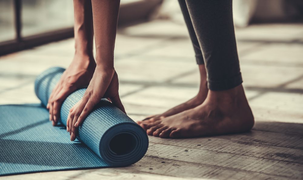 Woman unrolling a blue yoga mat before class