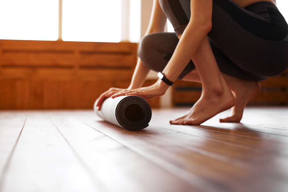 A woman rolling up her yoga mat after class