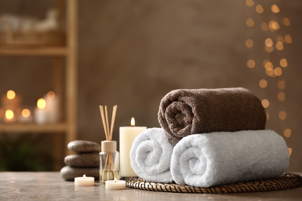 Spa towels and candles with diffuser on a grey marble table